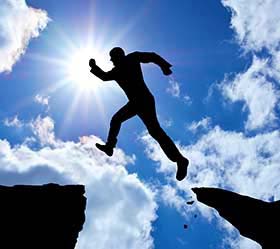 Person jumping a gap between rocks